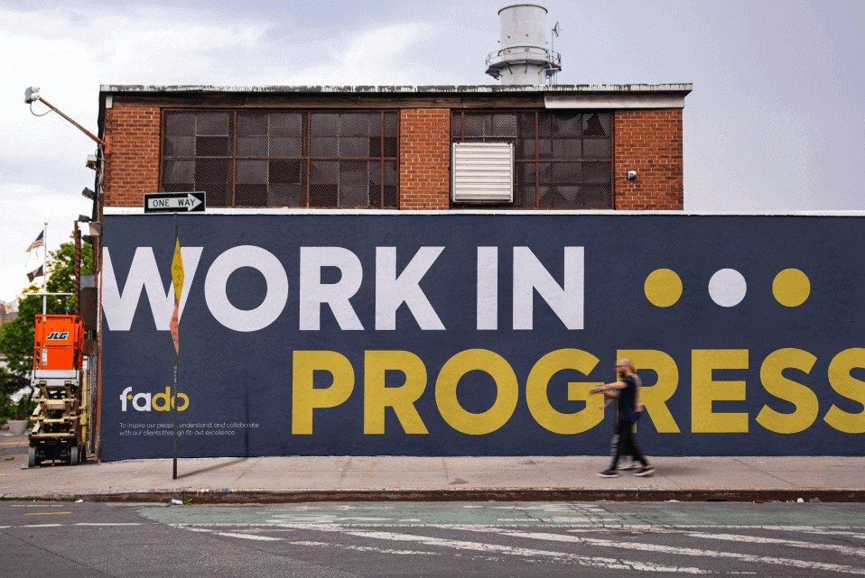 A Fado site hoarding reading Work in progress, on a street beside a scissor lift